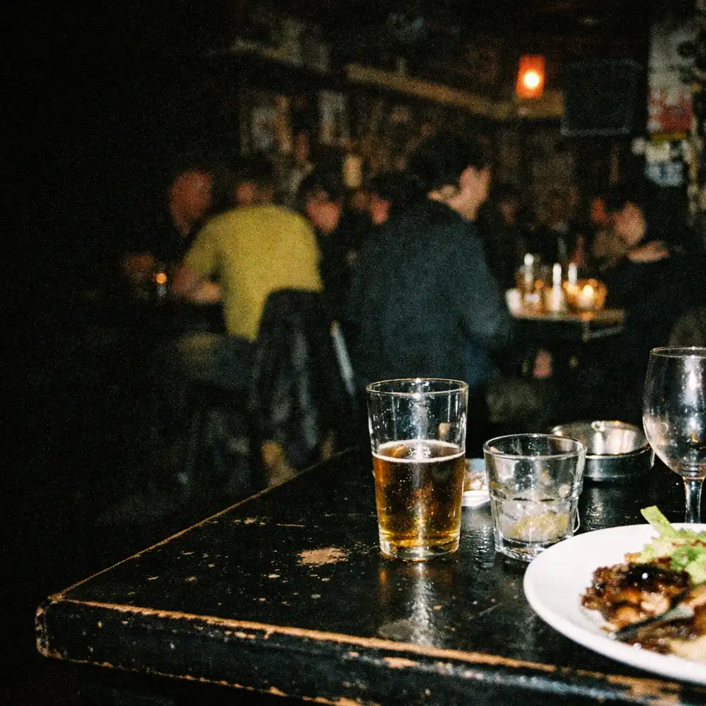 A flash-lit after-hours restaurant table with a plated meal and the dark dining room beyond